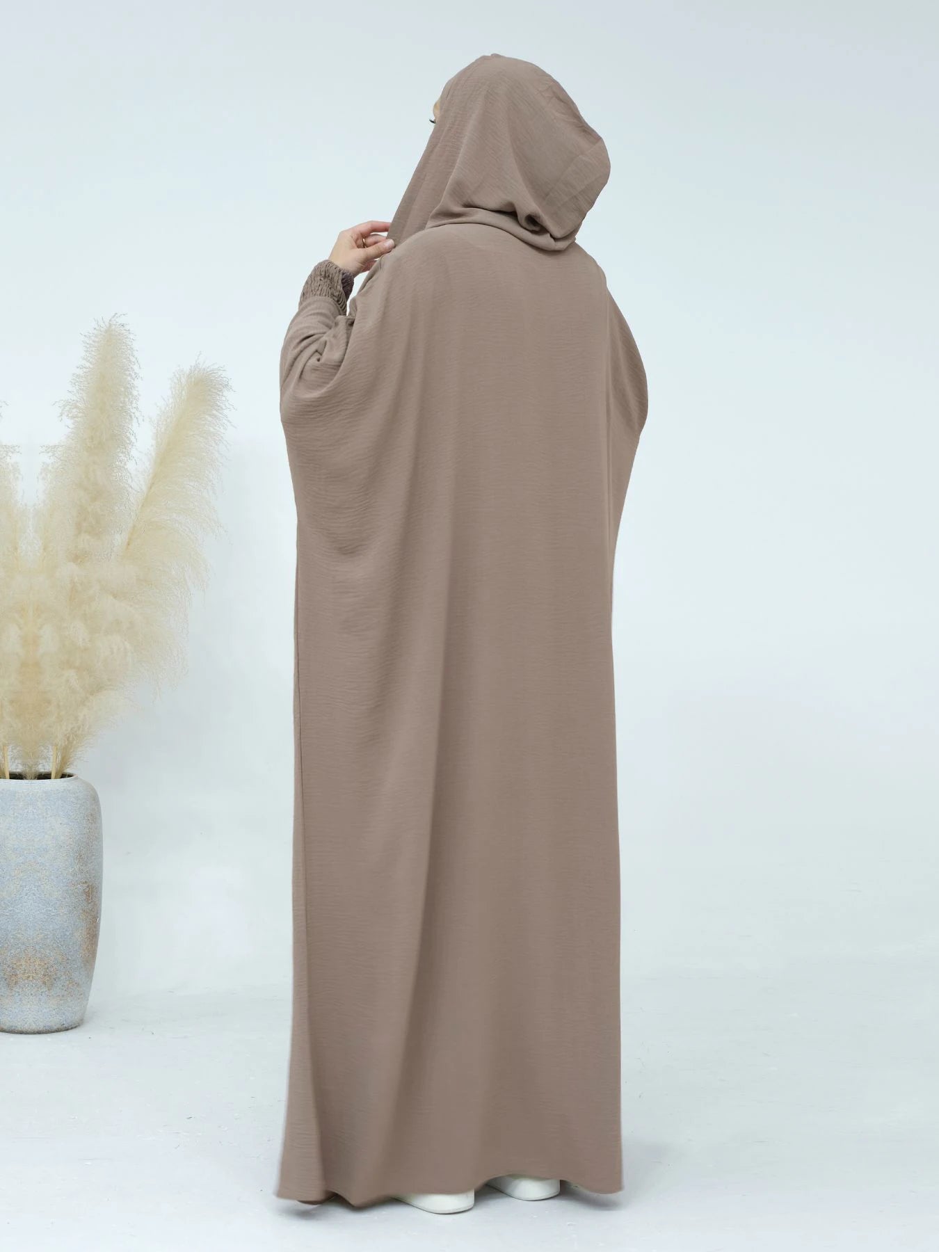 عباءة النسائية المزينة بتعليقات تضفي لمسة من الأناقة المرحة.